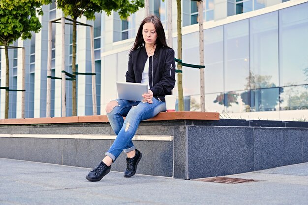 Aluna morena usando tablet PC em uma rua da cidade.