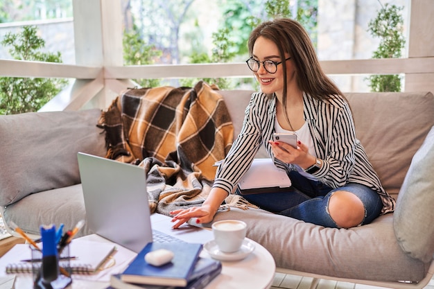 Aluna preety aprendendo em casa com o laptop e o telefone celular.