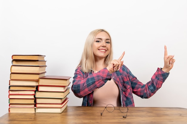 aluna sentada com diferentes livros em branco