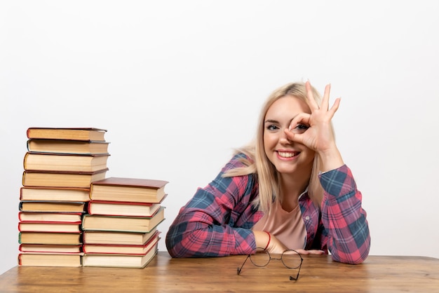 Aluna sentada com diferentes livros em branco