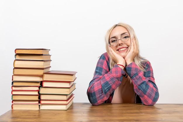 aluna sentada com diferentes livros em branco