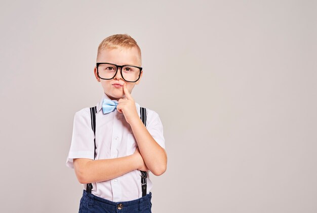 Aluno do ensino fundamental com a mão no queixo pensando