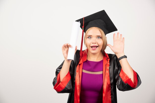 Aluno feliz no vestido recebeu o diploma na parede branca.