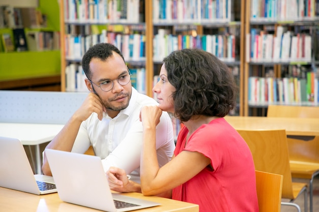 Alunos adultos sérios assistindo e discutindo webinar