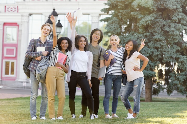 Alunos alegres em pé e acenando ao ar livre