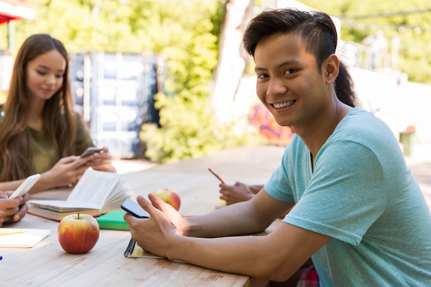 Alunos de jovens amigos multiétnico usando telefones celulares a sorrir