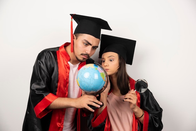 Alunos de pós-graduação frescos em vestido olhando globo em branco.