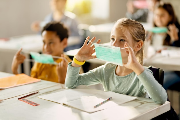 Alunos do ensino fundamental aprendendo a usar corretamente uma máscara durante uma aula na escola