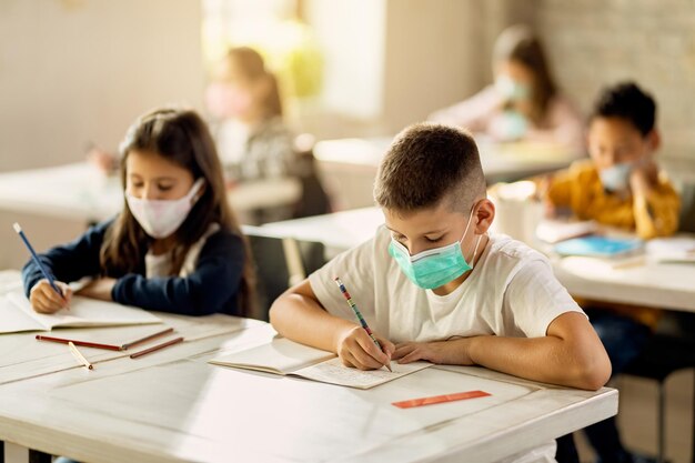 Alunos do ensino fundamental com máscara facial protetora de volta à escola após epidemia de coronavírus