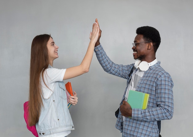 Foto grátis alunos felizes de tiro médio batendo alto