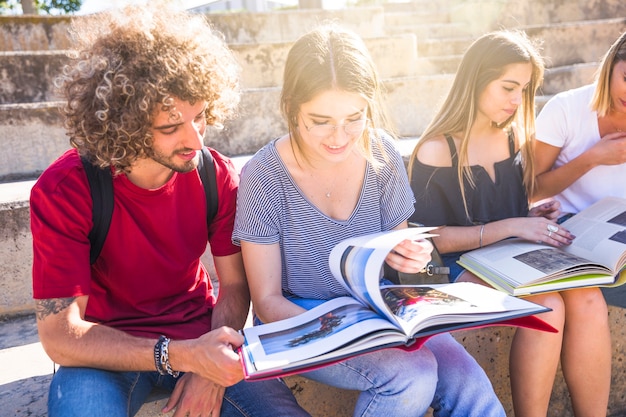 Alunos lendo livros didáticos em escadas