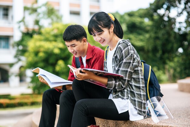 Alunos masculinos e femininos, sentado e lendo livros nas escadas.