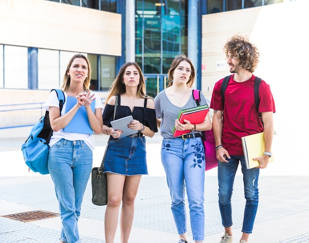 Alunos perplexos em pé perto do prédio da universidade