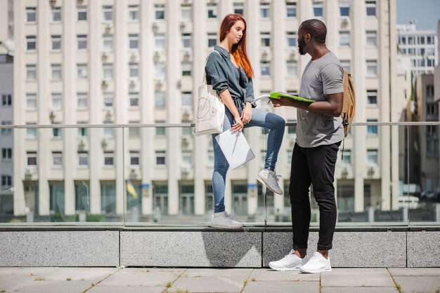 Alunos segurando cadernos falando na rua