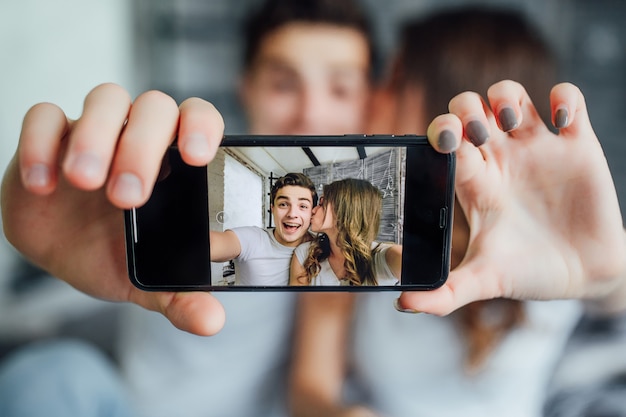 Amante feliz usando a tecnologia smart phone para selfie na cama do quarto em casa