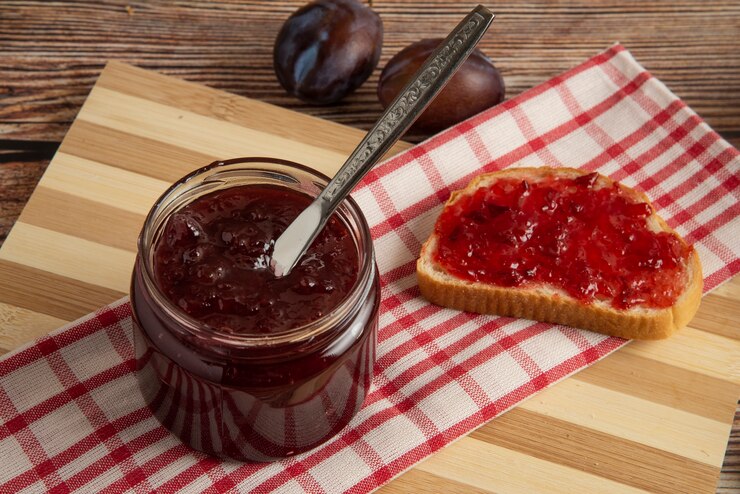 Foto grátis ameixas com um pote de doce e uma tosta de pão.