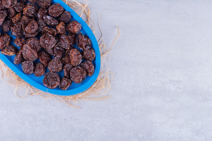 Foto grátis ameixas de cereja ácidas secas dentro de um prato isolado na superfície do concreto