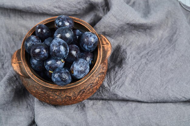 Ameixas de jardim em uma tigela na toalha de mesa cinza. foto de alta qualidade