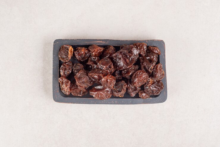 Foto grátis ameixas marrons secas em uma bandeja de madeira.