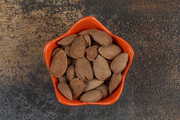 Amêndoas orgânicas com casca em uma tigela de laranja.