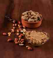 Foto grátis amendoim cru e descascado na tigela e manteiga de amendoim em fundo marrom de madeira