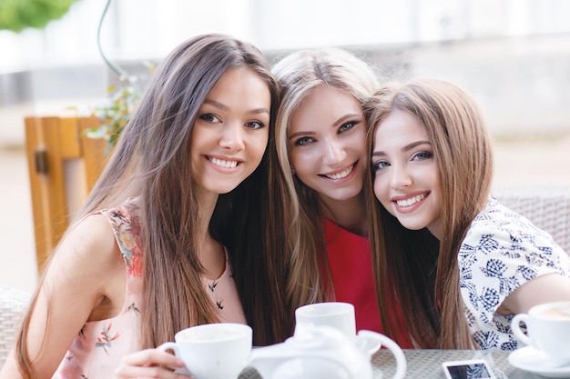 Amigas bonitas ao ar livre com café