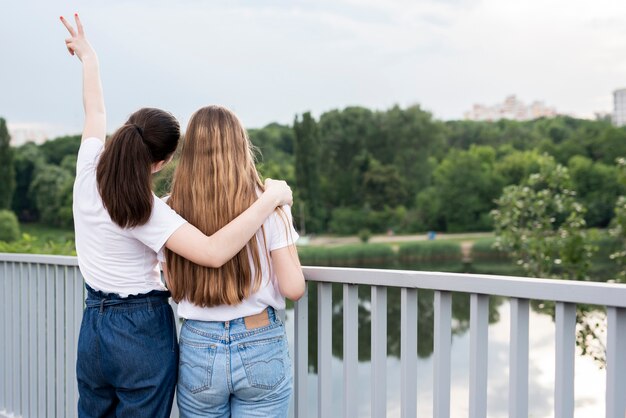 Amigas de vista traseira posando na ponte