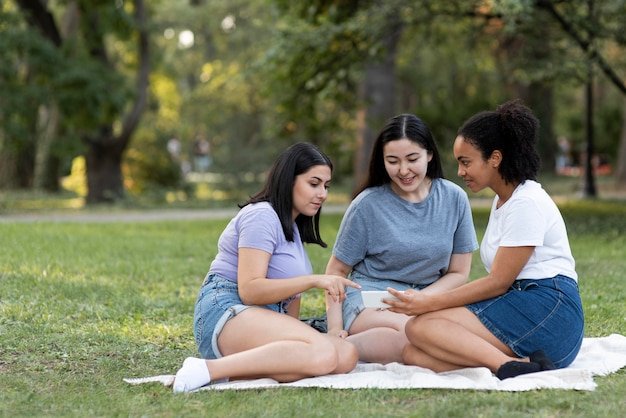 Amigas juntas no parque assistindo smartphone