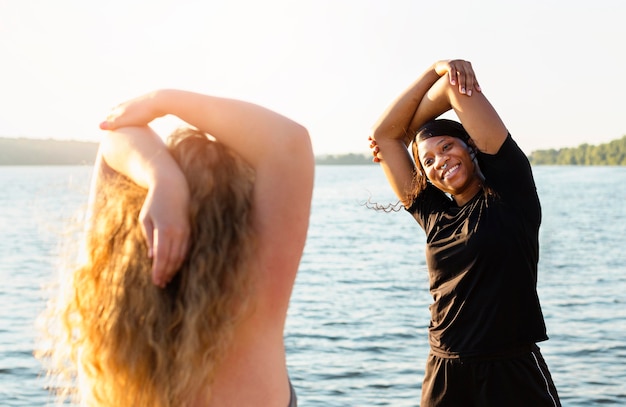 Amigas se exercitando à beira do lago