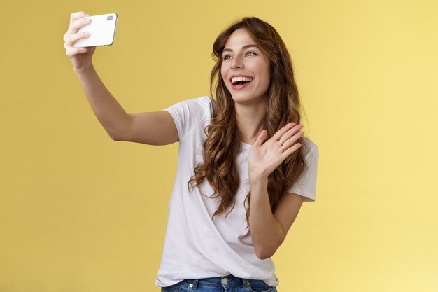 Amigável animada de boa aparência alegre menina feminina estender o braço segurar smartphone gravar vídeo blog wavi ...