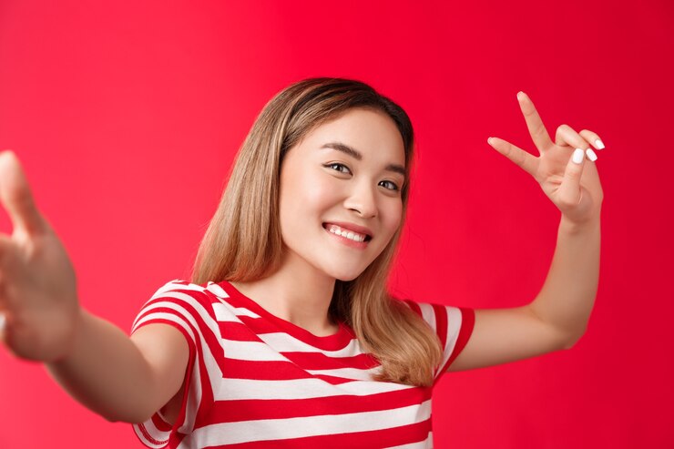 Foto grátis amigável extrovertido linda menina asiática loira curto penteado estender o braço segurar a câmera do smartphone inclinar a cabeça ...