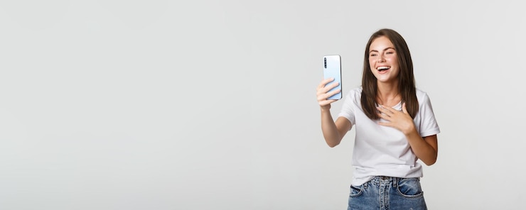 Foto grátis amigável mulher sorridente, fazendo chamadas de vídeo e falando no smartphone, fundo branco em pé feliz