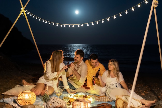 Amigos à noite na praia com cerveja e comida