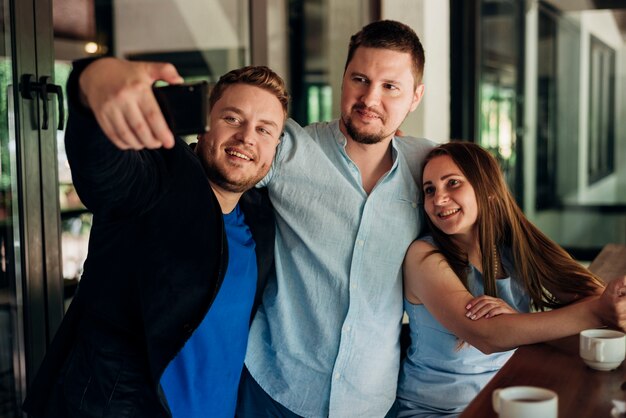 Amigos adultos que tomam selfie na sala de jantar