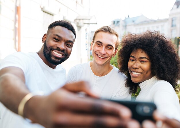 Amigos alegres ao ar livre, tendo selfie