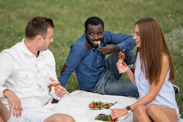 Amigos ao ar livre na natureza comendo churrasco