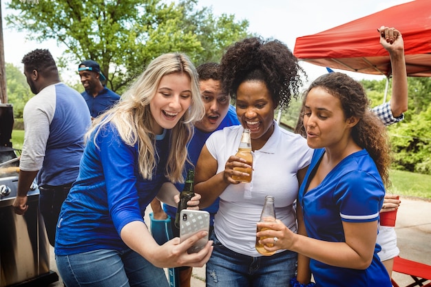 Foto grátis amigos assistindo ao jogo em um telefone em uma festa ao ar livre