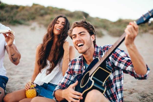 Amigos com guitarra cantando na praia