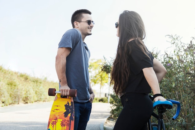 Amigos com longboard e bicicleta tendo conversa