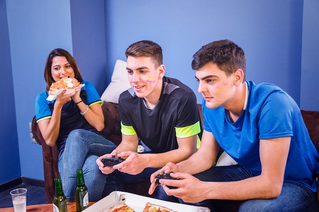 Amigos comendo pizza e assistindo futebol