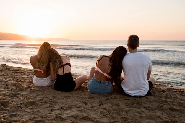 Amigos completos sentados na praia