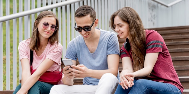 Amigos de baixo ângulo olhando no celular