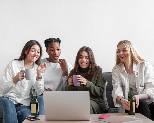 Foto grátis amigos de baixo ângulo olhando para laptop