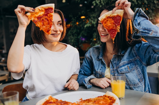 Amigos de menina com pizza em um bar na hora do almoço