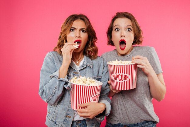 Amigos de mulheres chocados comendo pipoca assistir filme.