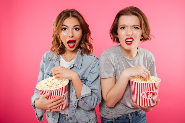 Amigos de mulheres chocados comendo pipoca assistir filme.