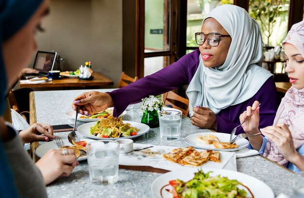 Amigos de mulheres islâmicas jantando juntos com felicidade