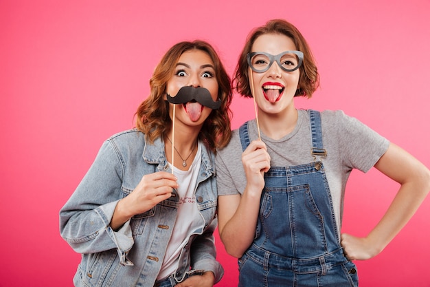 Amigos de senhoras engraçadas segurando óculos e bigode falso.