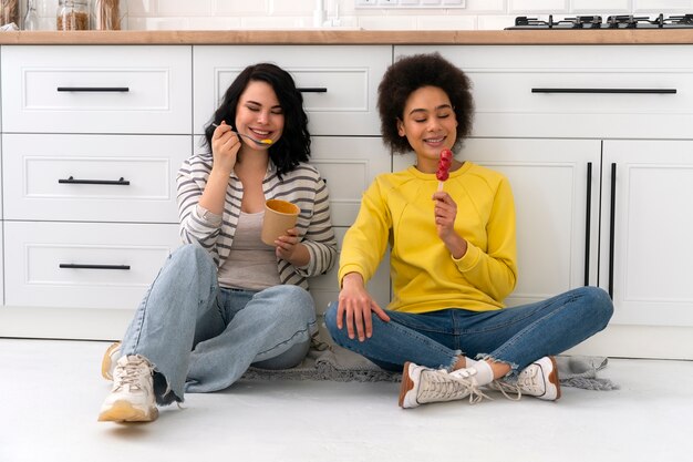 Amigos de tiro completo comendo sorvete dentro de casa