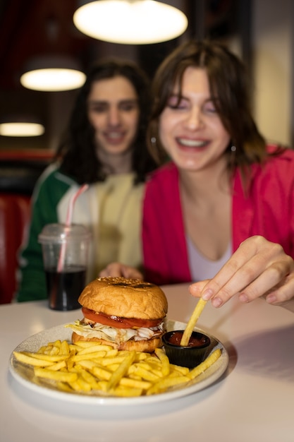 Amigos de tiro médio comendo fast food de uma forma engraçada